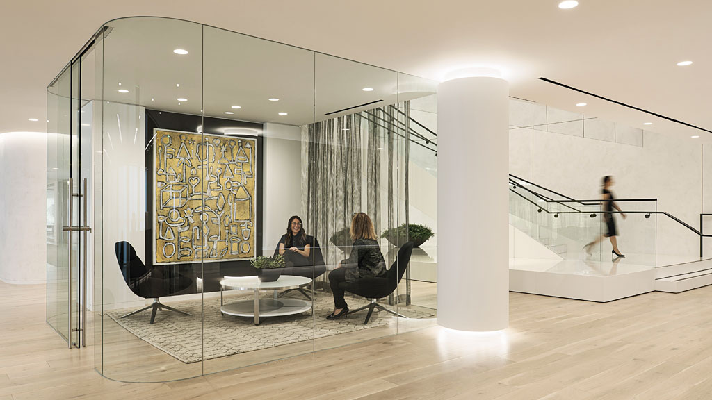 A group of people sitting at a table in a room with glass walls.