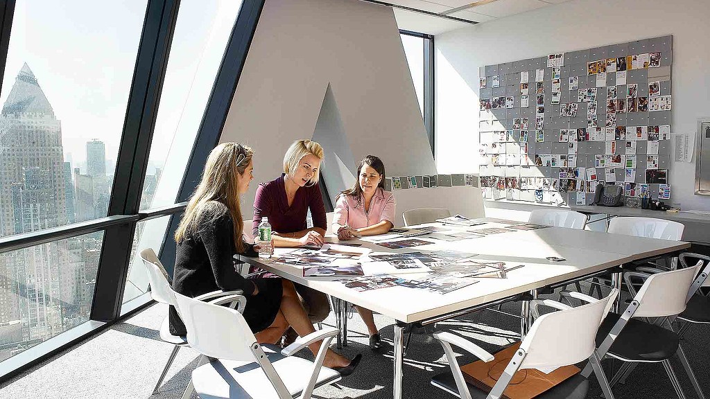 A group of women sitting at a table with a city skyline in the background.