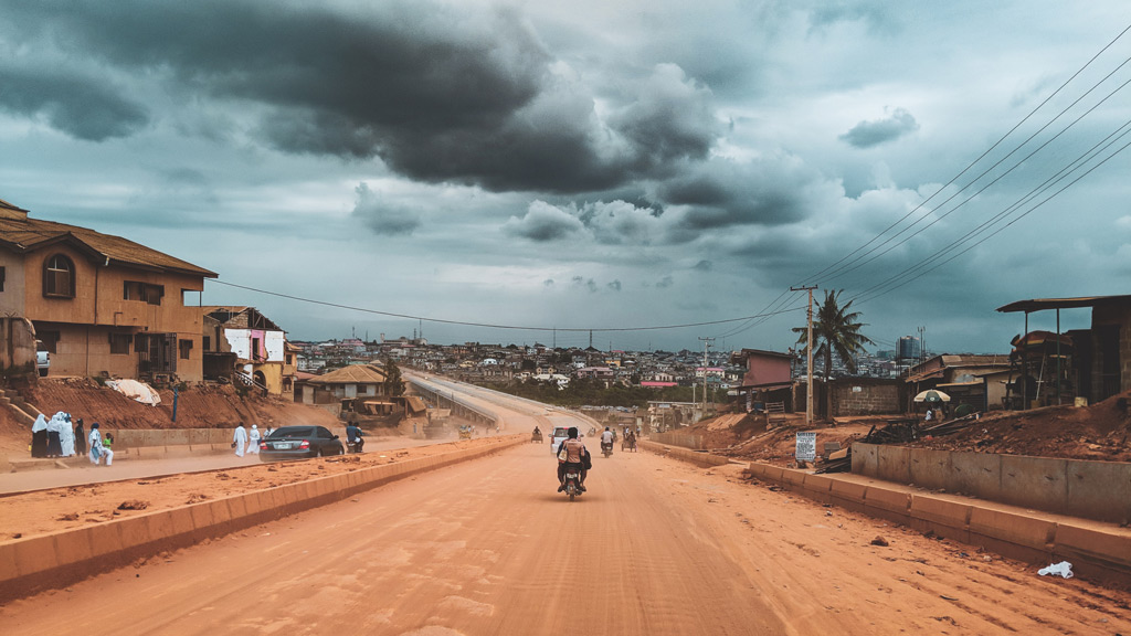 A road with a motorcycle and buildings on the side.