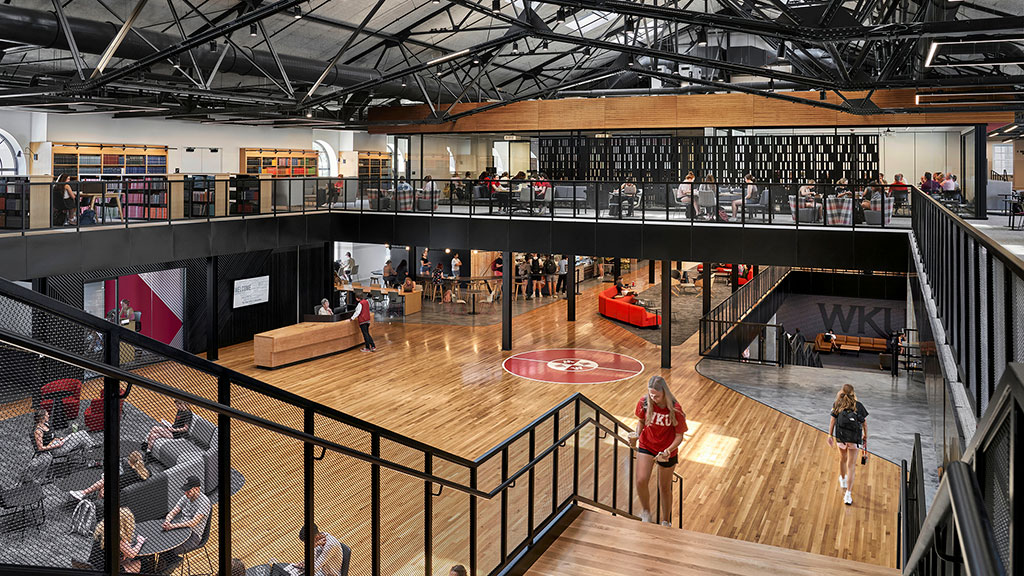 A group of people in a large room with a basketball court.